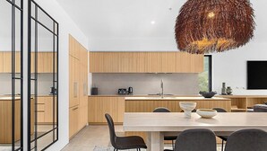 Uma cozinha moderna com armários de madeira, uma área de refeições com uma mesa grande e cadeiras, e um lustre.
