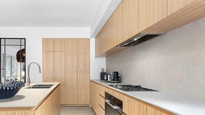 Uma cozinha moderna com armários de madeira, uma ilha central com uma tigela azul e um fogão.