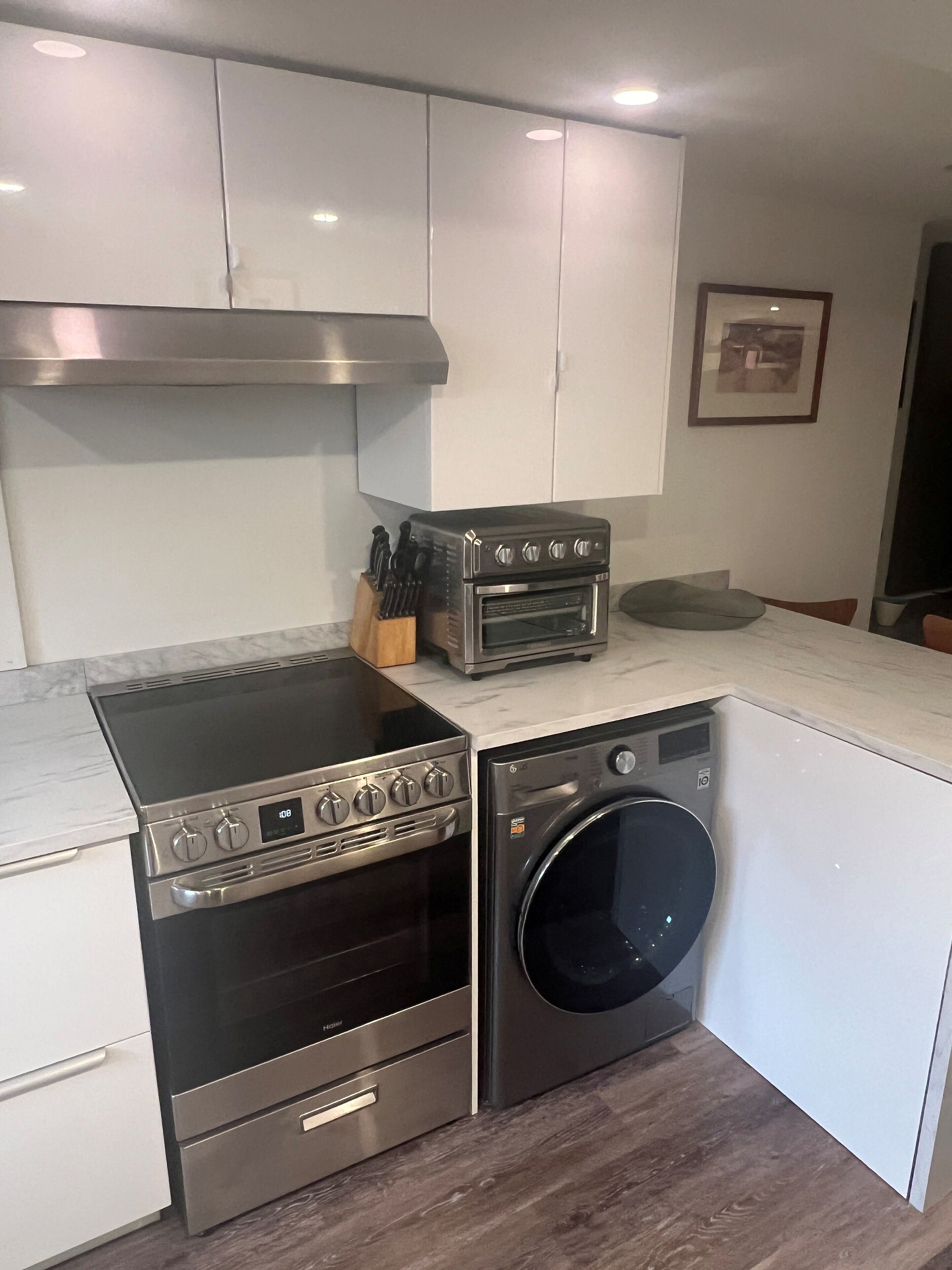 A compact kitchen with a built-in oven, microwave, and washing machine.