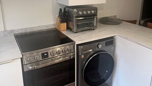 A compact kitchen with a built-in oven, microwave, and washing machine.