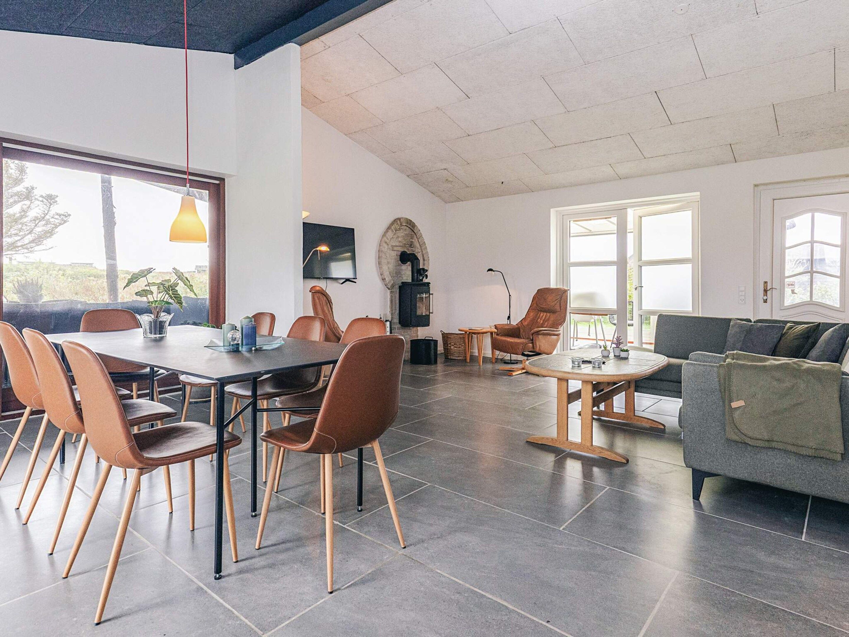 A modern living room with a dining area, large windows, and a fireplace.