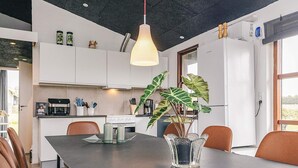 Ett modernt kök med vita skåp, en köksö och en hängande taklampa.