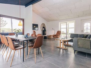 A spacious living area with a dining table, chairs, a sofa, and a fireplace.