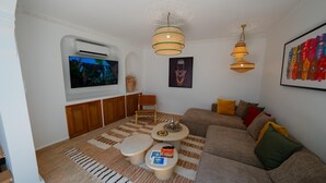 Una sala de estar con televisor, sofá, mesa de centro y un sillón decorativo.