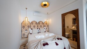 A hotel room with a bed, a large mirror, and a wooden door. - Riad II Ksour Exclusif Rooftop View & Jacuzzi (Marrakech)