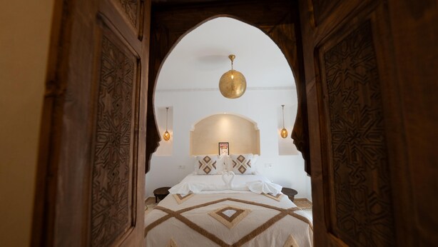 Una habitación de hotel con una cama, una araña y un arco decorativo.