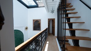 Una escalera con escalones de madera y barandillas de metal negro que conduce a una plataforma con tragaluz y un aplique decorativo en forma de estrella.