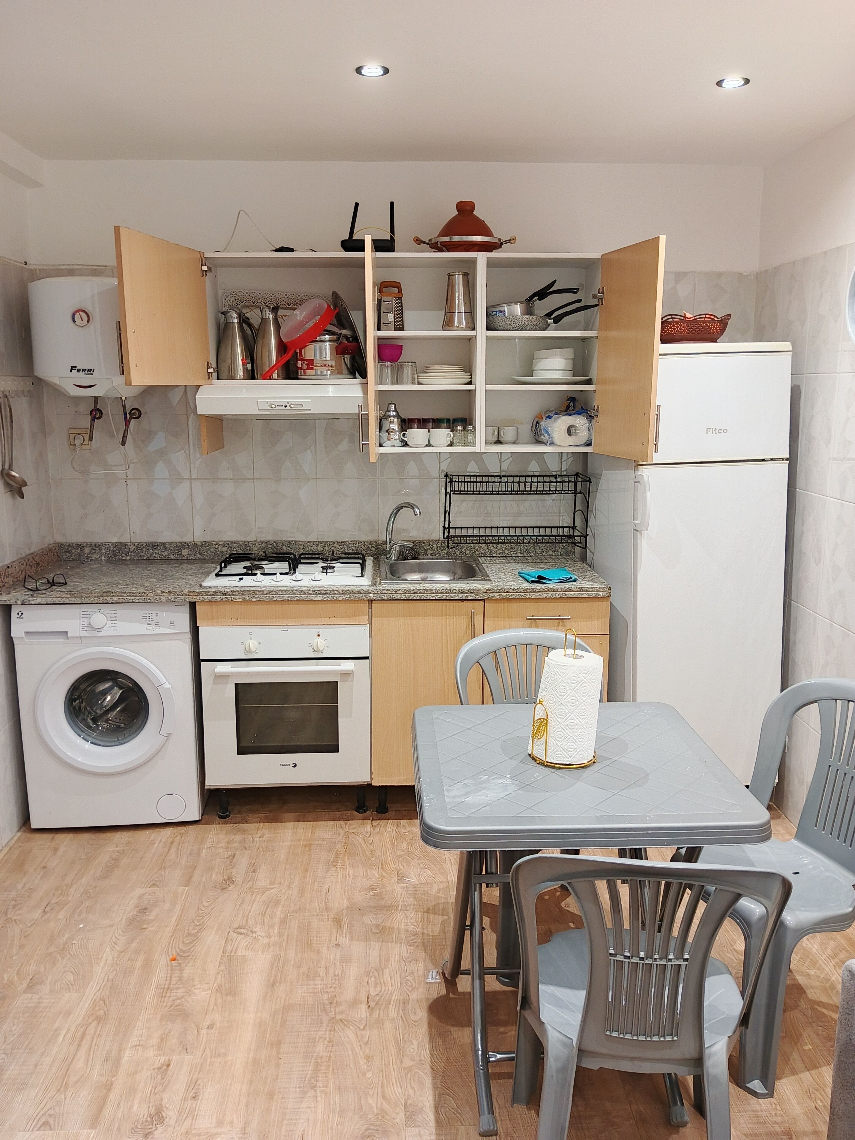 A compact kitchen with a washing machine, oven, and a dining area with chairs.