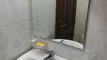 A bathroom with a white sink, a mirror, and a glass soap dish.