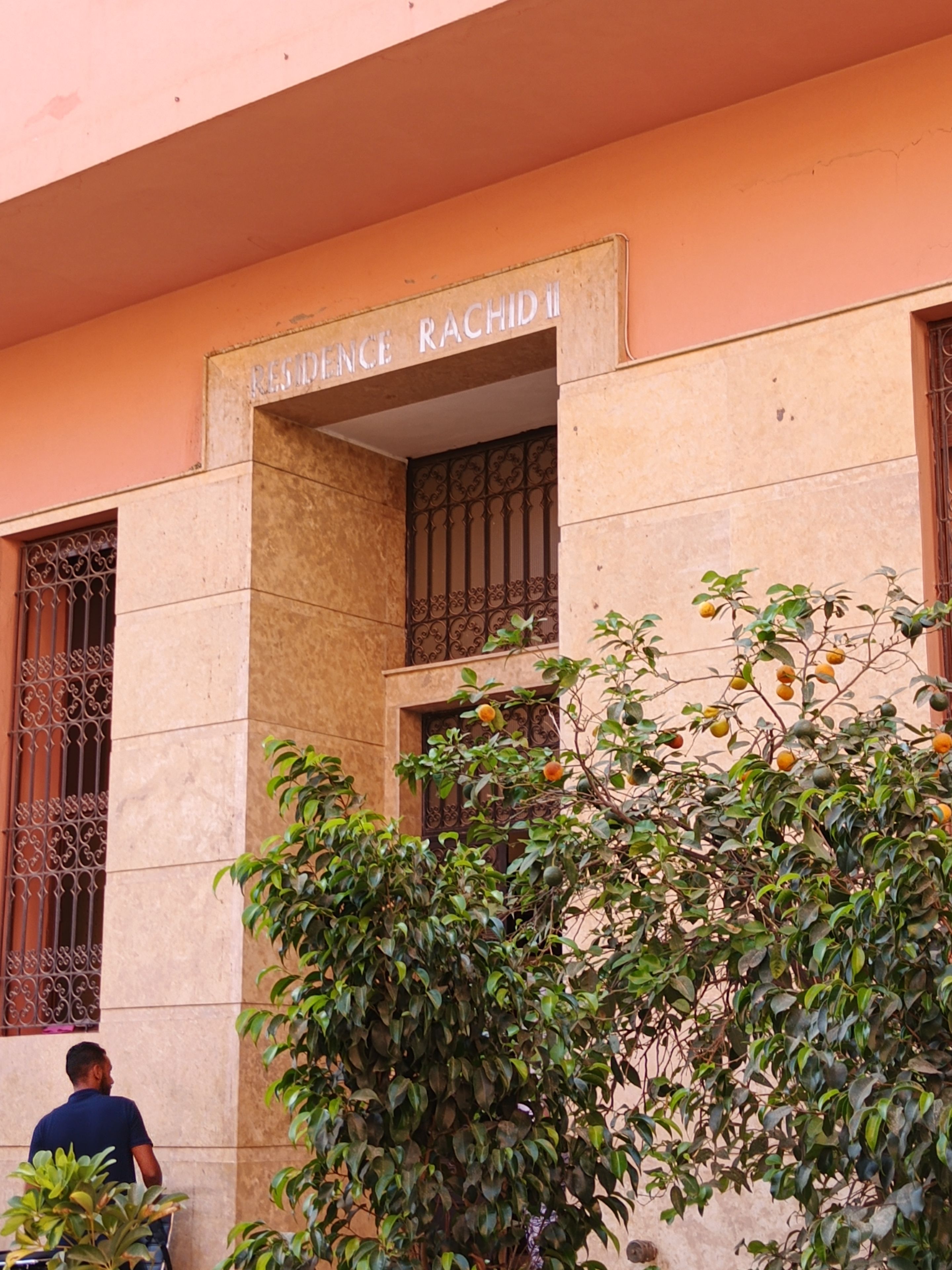 A building with a sign reading 'Residence Rachidi' above a gated entrance.