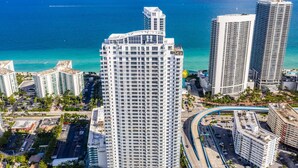 A high-rise hotel with multiple floors, a swimming pool, and a view of the ocean.