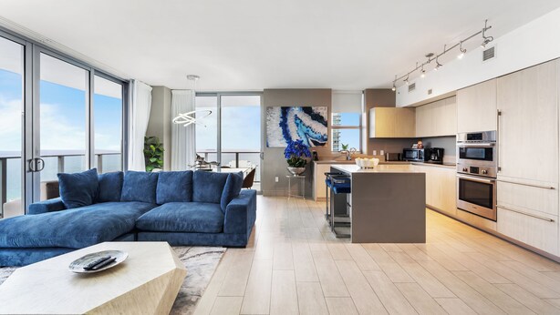 A modern apartment with a large living area, a kitchen, and a balcony with a view.