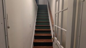 A narrow hallway with a staircase leading to a door with a window. - Perfectly Located 1 Bedroom, newly remodeled  (Augusta)