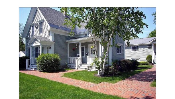 A two-story house with a front porch, a small tree, and a brick pathway. - Perfectly Located 1 Bedroom, newly remodeled  (Augusta)