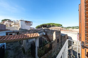 A view of a courtyard with stone walls, a tiled roof, and a wooden balcony railing. - Apartment 'Domenico' with Balcony, Wi-Fi and Air Conditioning (Castanea delle Furie)