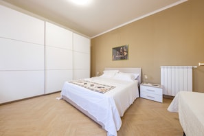 Een slaapkamer met een groot bed, een nachtkastje, een radiator en een aan de muur hangend schilderij.