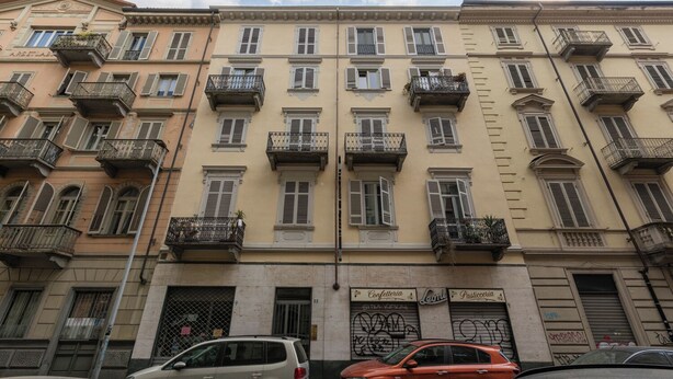 Un immeuble à plusieurs étages doté de balcons, une enseigne indiquant une confiserie et une pâtisserie.