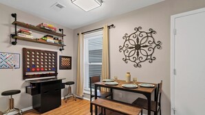 A dining area with a wooden table set for four, a chessboard, and shelves with board games. - Dog friendly 1st floor  King bd in Ocean Ridge (Edisto Island)