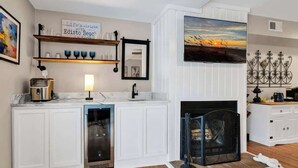 A modern kitchen with white cabinetry, a built-in oven, a coffee maker, and a fireplace. - Dog friendly 1st floor  King bd in Ocean Ridge (Edisto Island)