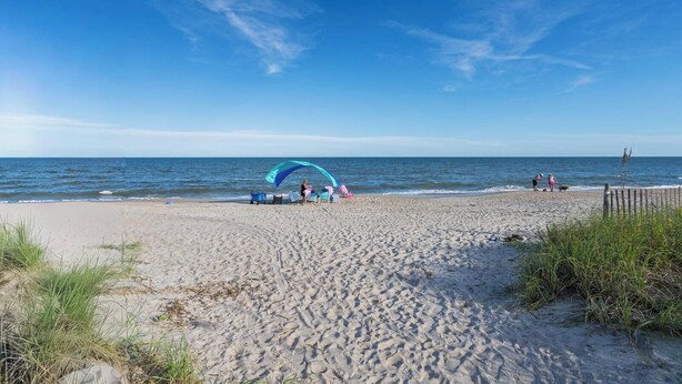 A beach with a large umbrella and beach chairs, a sandy shore, and the ocean in the background. - Dog friendly 1st floor  King bd in Ocean Ridge (Edisto Island)