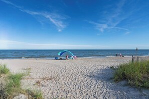 A beach with a large umbrella and beach chairs, a sandy shore, and the ocean in the background. - Dog friendly 1st floor  King bd in Ocean Ridge (Edisto Island)
