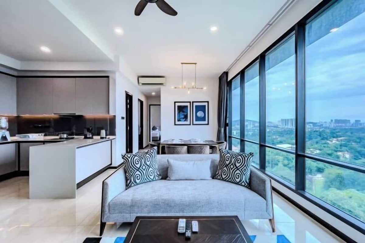 A modern living room with a sofa, a coffee table, and a view of a cityscape through large windows.
