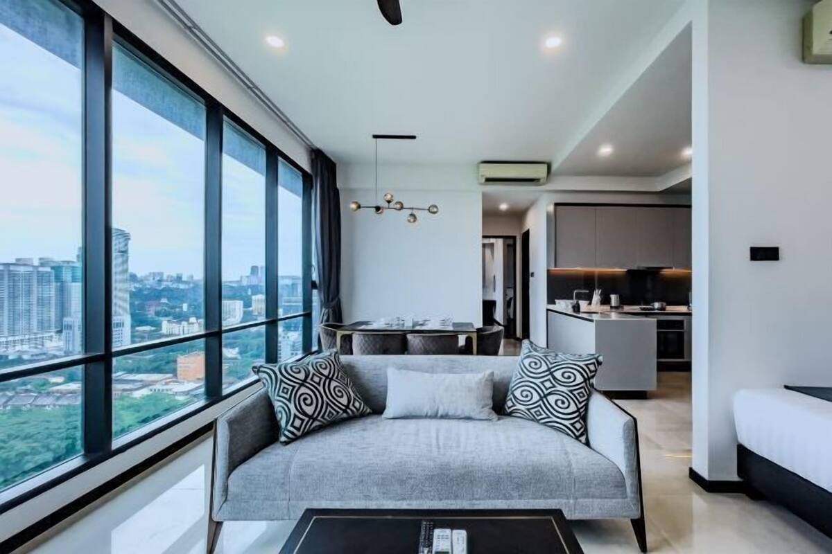 Una sala de estar moderna con un sofá, una mesa de centro y vistas de la ciudad a través de amplias ventanas.