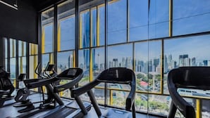 A gym with treadmills and exercise equipment, large windows with a cityscape view. - Opus Residences by Wakely Kuala Lumpur (Kuala Lumpur)
