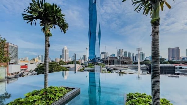 A rooftop infinity pool with palm trees and a city skyline in the background. - Opus Residences by Wakely Kuala Lumpur (Kuala Lumpur)