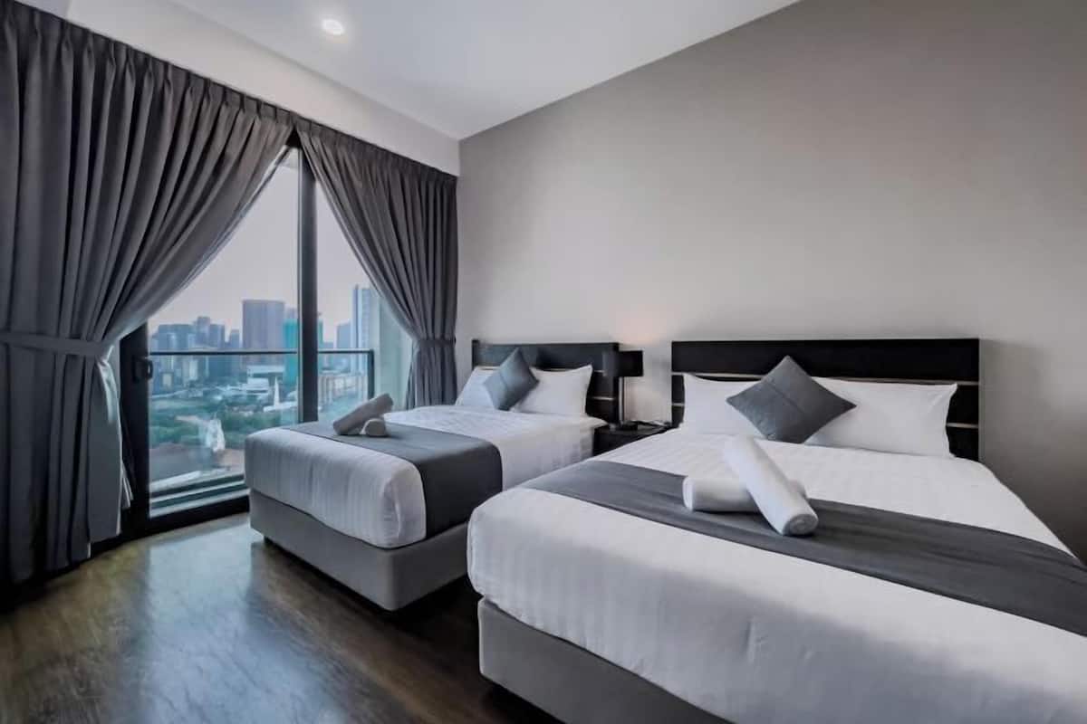 A hotel room with two beds, a city view, and a large window with curtains.