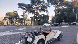 Une voiture décapotable ancienne est garée sur une rue pavée.