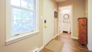 A hallway with a wooden floor, a white door, and a window with a view of trees. - Jiminy Peak Slopeside Getaway • Ski & Adventure (Hancock)