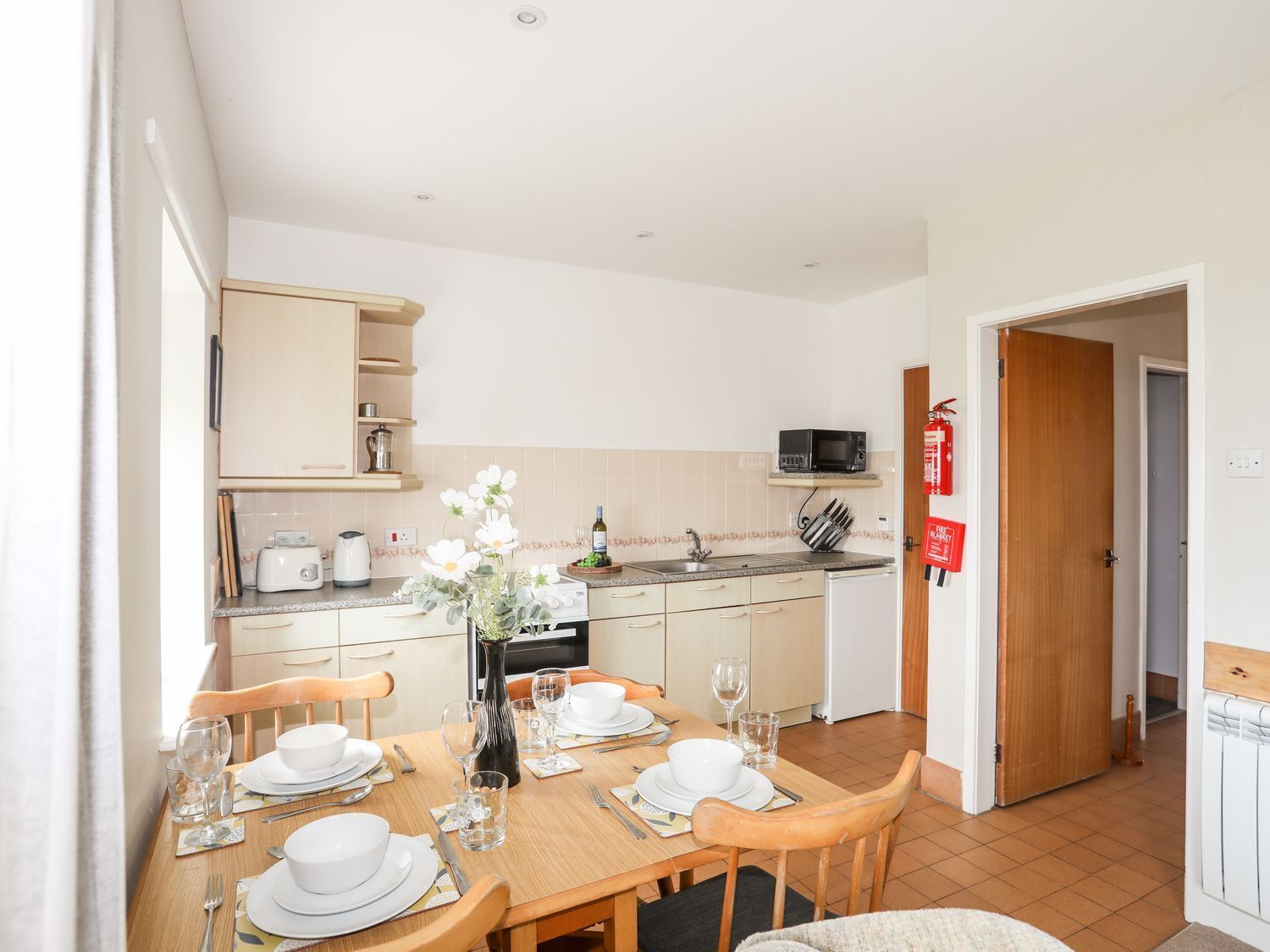 A compact kitchen with a dining area, equipped with basic appliances and a small table set for two.