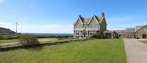 A large, two-story house with a prominent front entrance and a driveway leading to a garage.