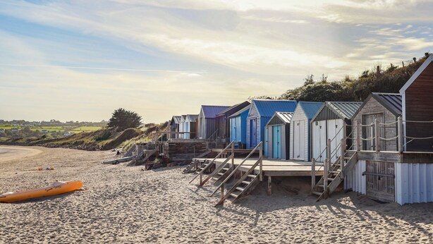A row of beach huts with wooden stairs leading up to them, situated on a sandy beach with a clear sky. - Ysgo - 6 Ty'n Don (Pwllheli)