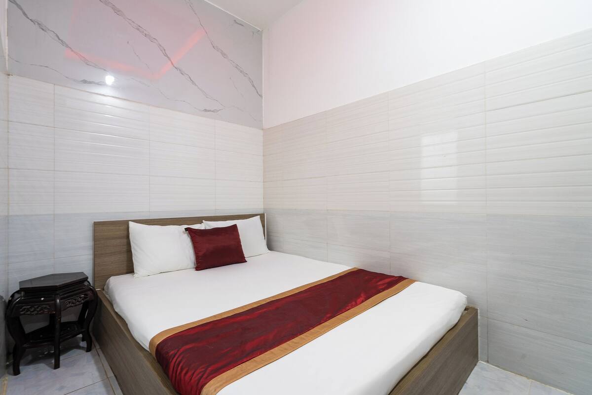 A hotel room with a large bed, a nightstand, and marble-patterned walls.