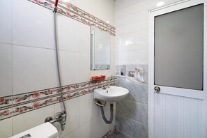 Une salle de bain avec un lavabo blanc, un miroir, une douche et des toilettes.