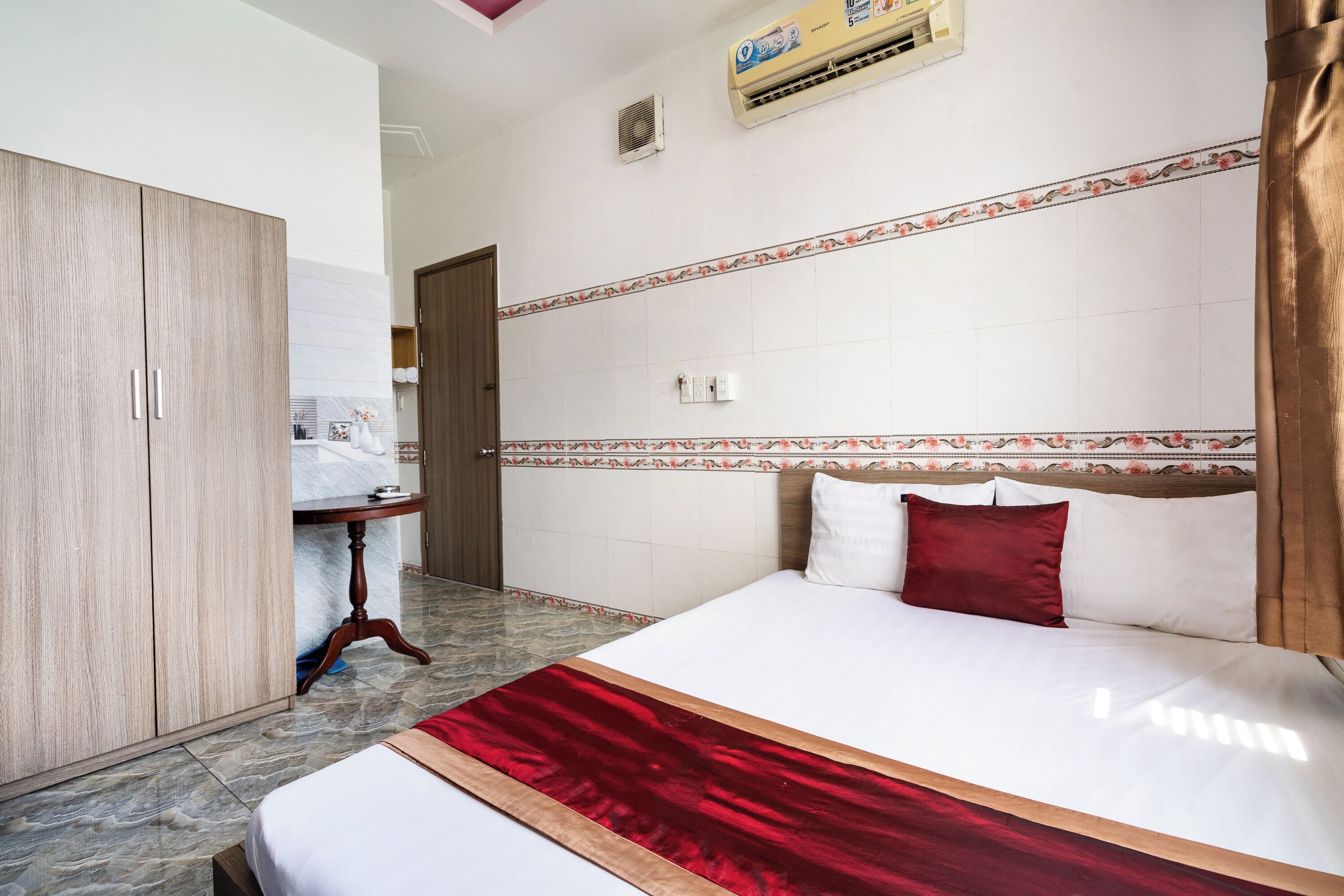 A hotel room with a bed, wardrobe, and a small table.