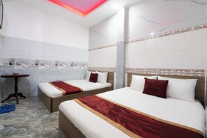 Une chambre d’hôtel avec deux lits, des murs en marbre et un mur d’accent rouge.