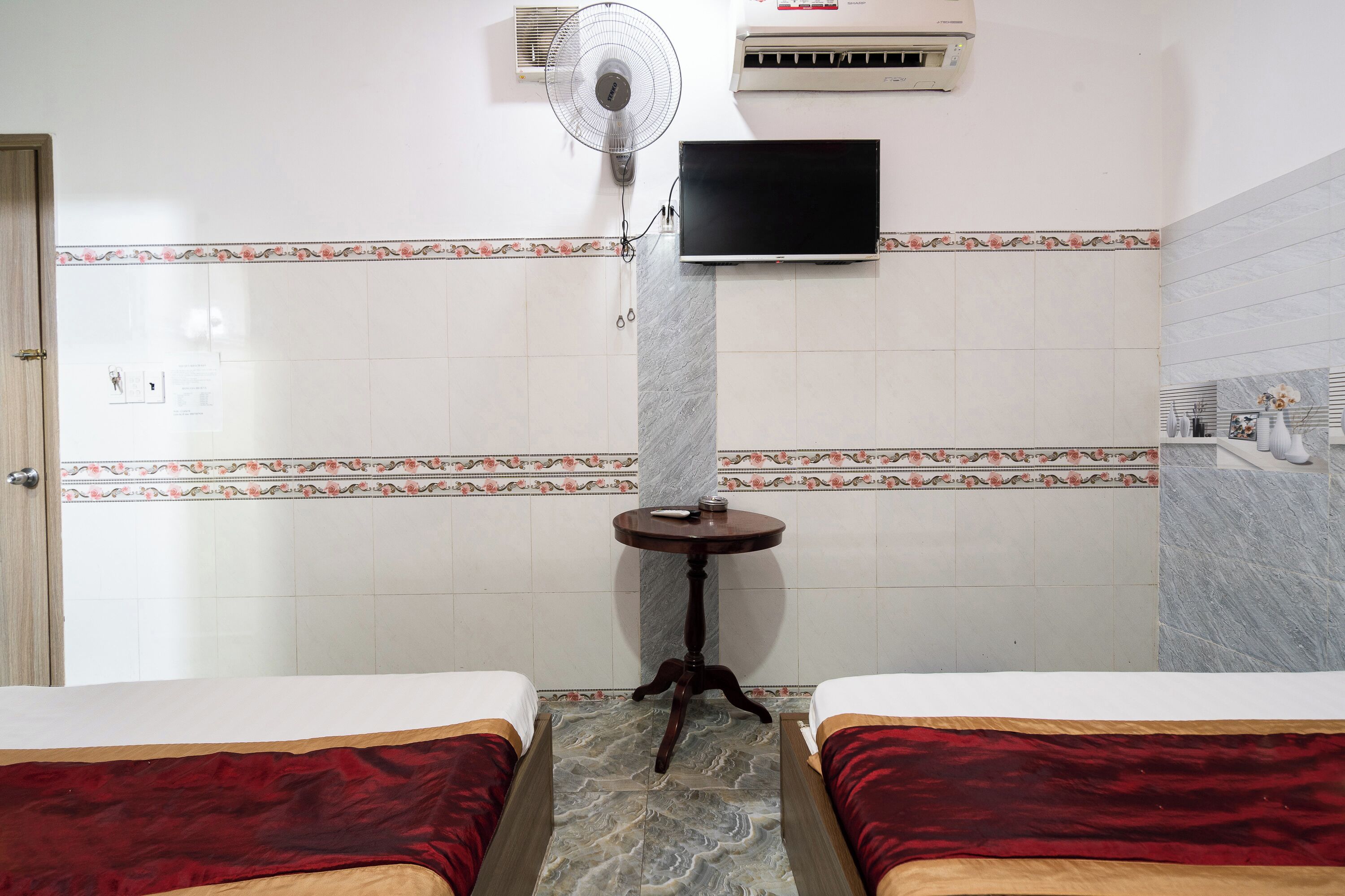 Una habitación de hotel con dos camas, televisión, aire acondicionado y ventilador.