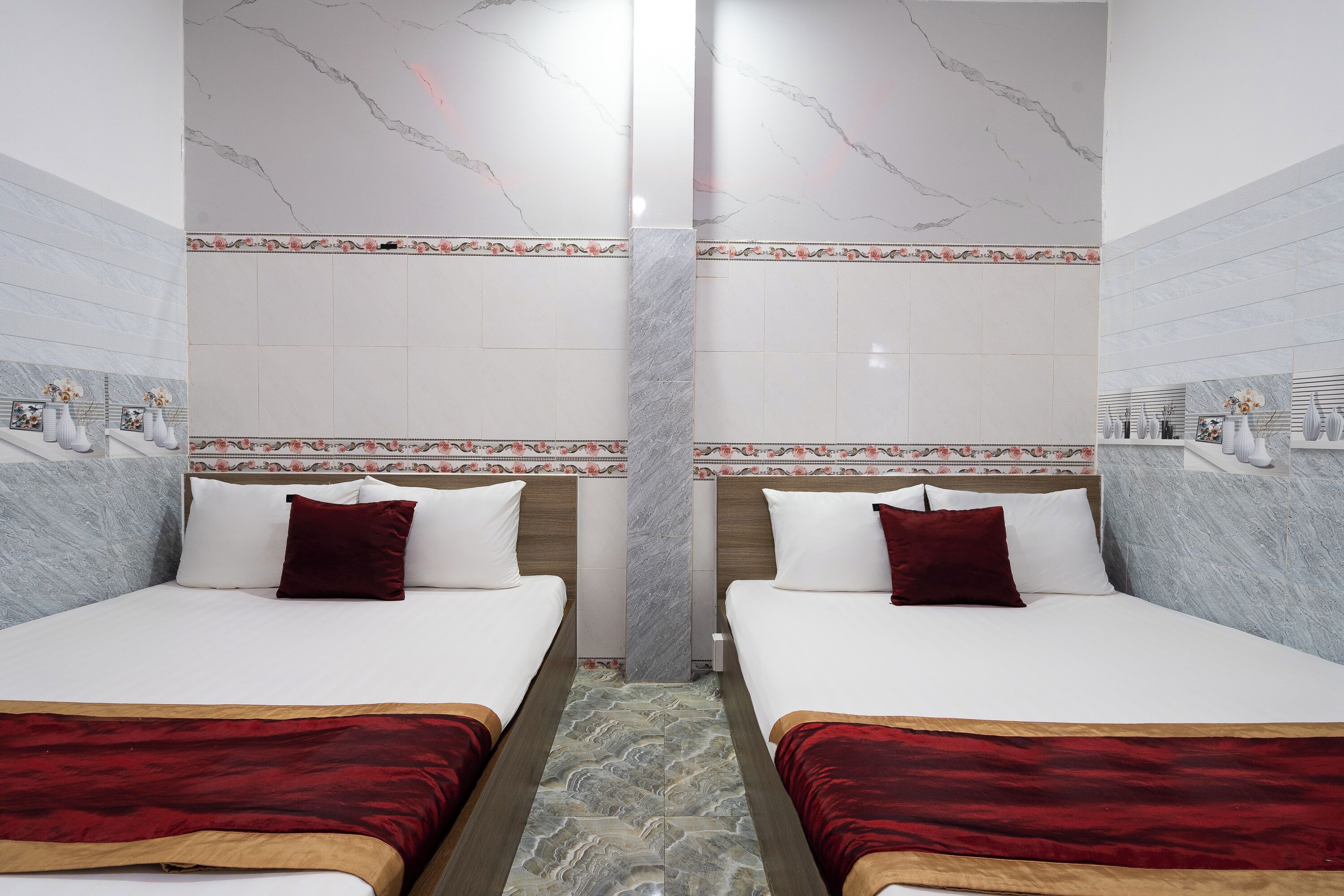 Ein Hotelzimmer mit zwei Betten, Marmorwänden und einer dekorativen Bordüre.
