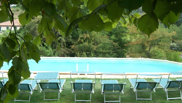 A poolside area with lounge chairs and a view of a clear blue pool surrounded by greenery. - Villa 'Olivi' with Shared Pool, Private Garden and Wi-Fi (Nocchi)