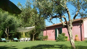 A garden with a table and chairs, a tree, and a building with a red roof. - Villa 'Olivi' with Shared Pool, Private Garden and Wi-Fi (Nocchi)