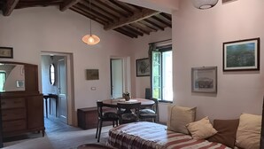 A cozy room with a bed, a dining table, and a bench. There are framed pictures on the walls and a window providing natural light. - Villa 'Olivi' with Shared Pool, Private Garden and Wi-Fi (Nocchi)