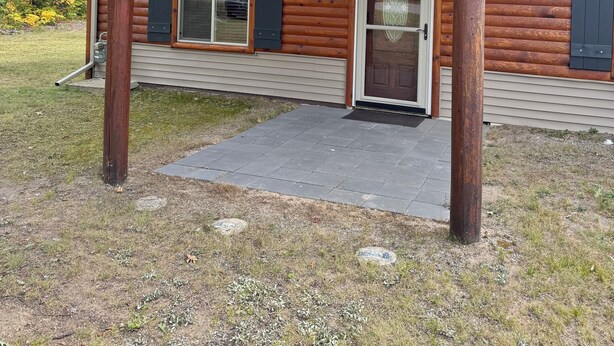 En hytte med træfacade, en overdækket veranda, en hoveddør og en garageport.