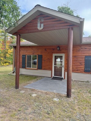 A log cabin with a covered porch, a front door, and a garage door. - Little Lodge on Big Antler (Lewiston)