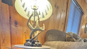 Et træbord med en base formet som en bjørn, en lampe og en sofa i baggrunden.