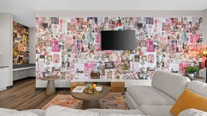 Una sala de estar moderna con una gran composición de fotos en la pared, un televisor de pantalla plana, un sofá y una mesa de centro.