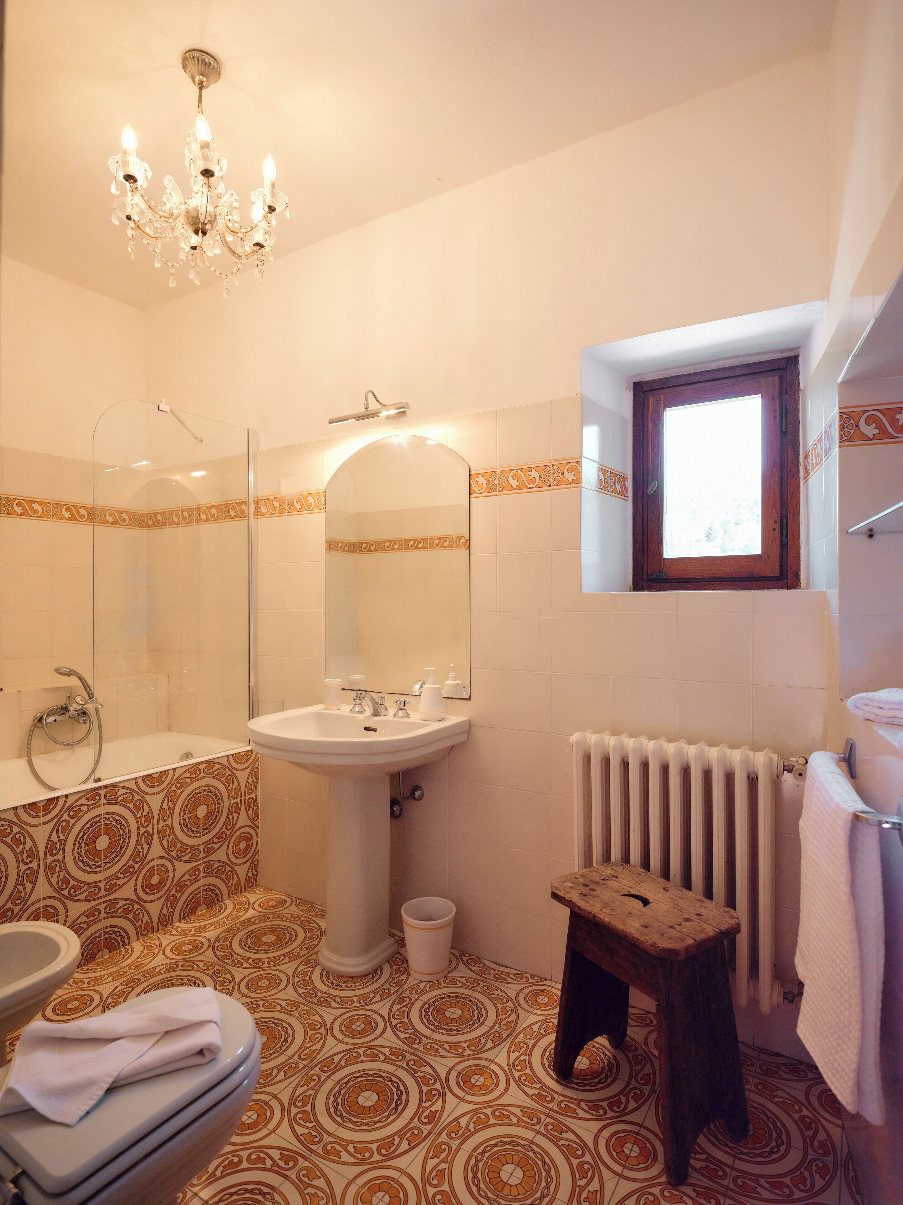 Une salle de bain avec une douche, un lavabo, des toilettes et une petite fenêtre.