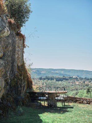 A rustic outdoor seating area with a stone table and metal chairs, overlooking a scenic landscape. - Le Convertoie: Tuscan Villa with Pool & History (Toscana)